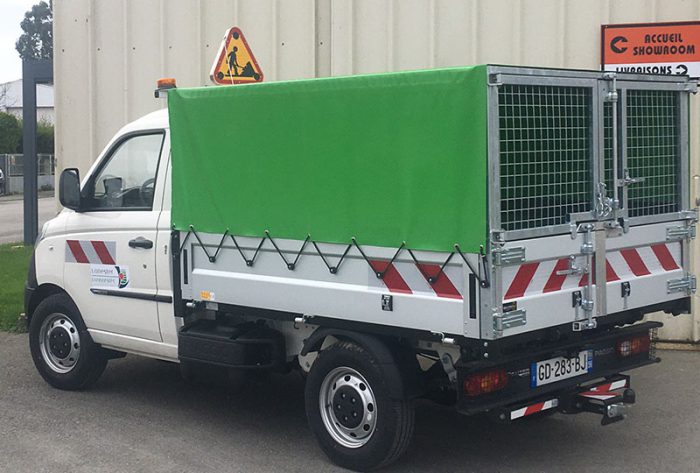 Bâche de protection verte installée sur un camion de commune pour le protéger des intempéries.