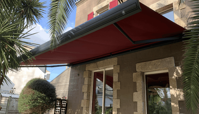 Store banne motorisé avec toile rouge installé sur terrasse