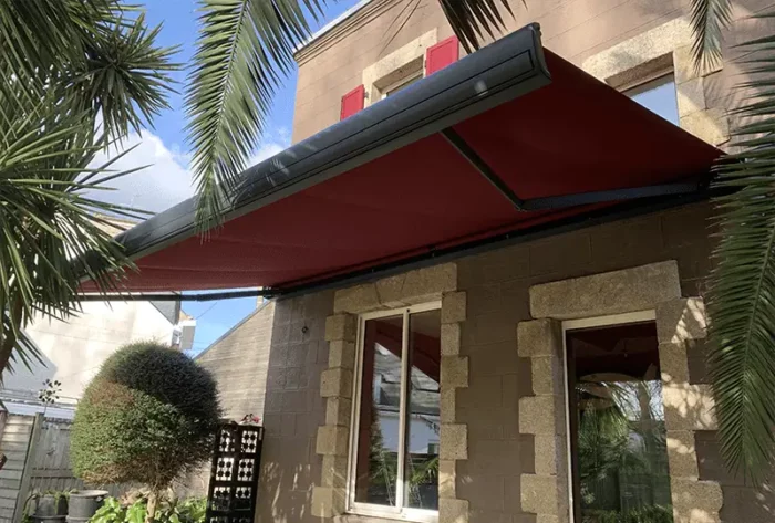 Store banne motorisé avec toile rouge installé sur terrasse